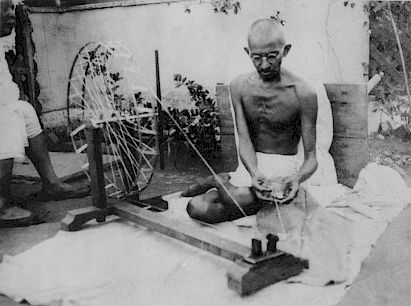 Mohandas Gandhi sitting at a charka (spinning wheel), symbol of Indian self-reliance and contrast to the mechanized, globalized world of British colonialism
