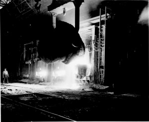 A steel worker pouring pig iron in a Jones & Laughlin steel mill in Pittsburgh, c. 1920s.